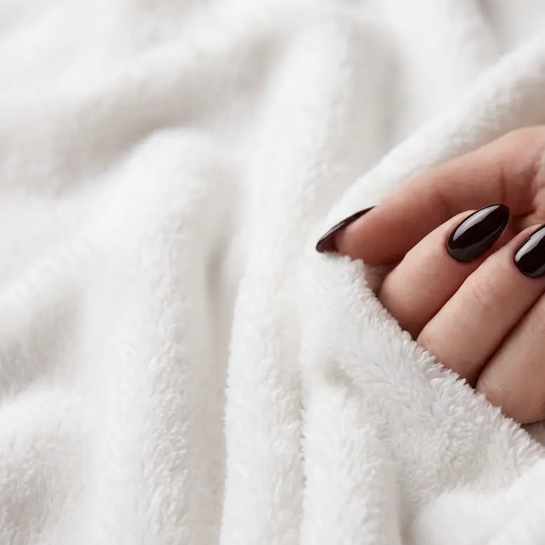 White plush texture up close with a manicured hand